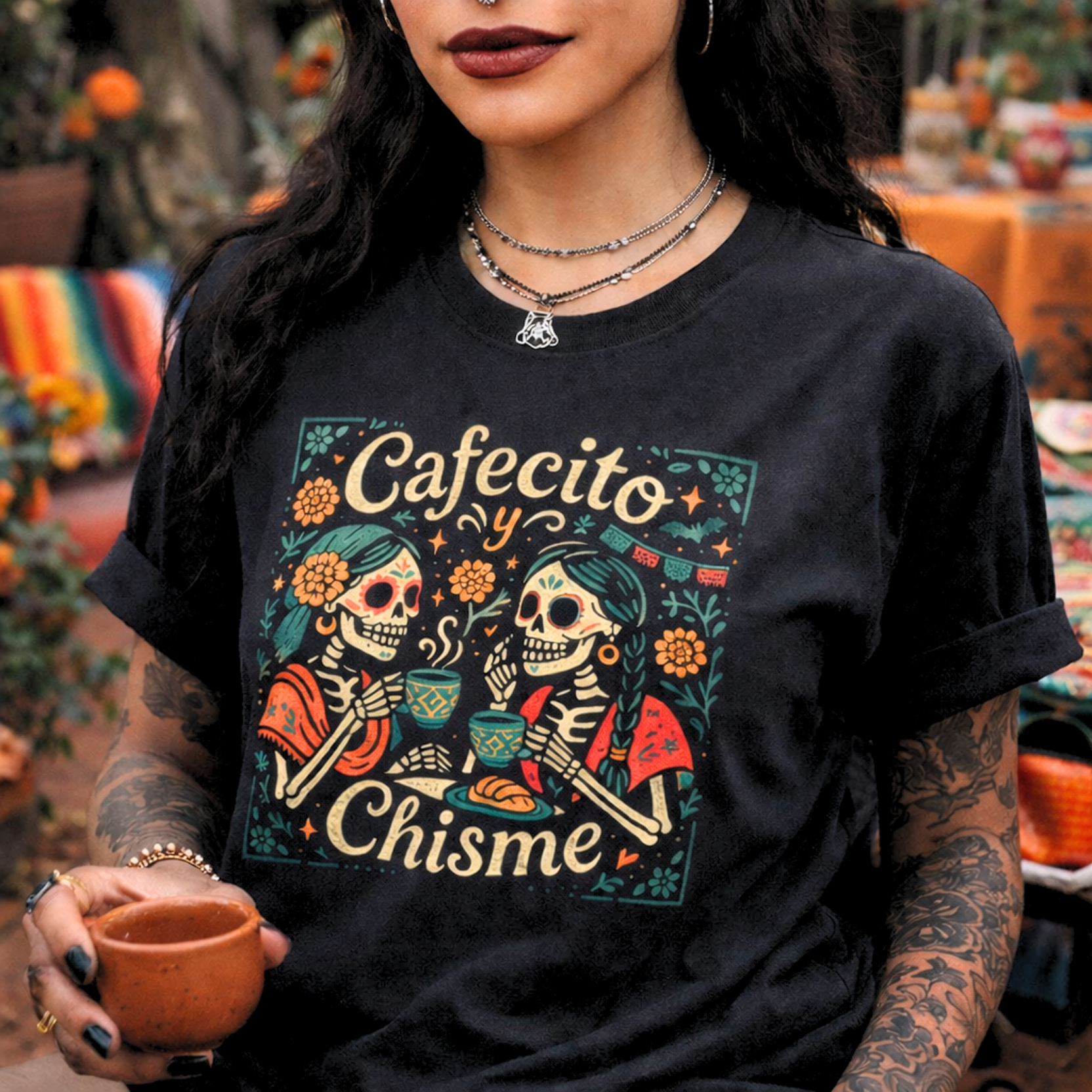 Bone Threads black Cafecito y Chisme Skeleton Graphic Tee featuring two Calaveras drinking coffee and pan dulce—Latina Culture Shirt.